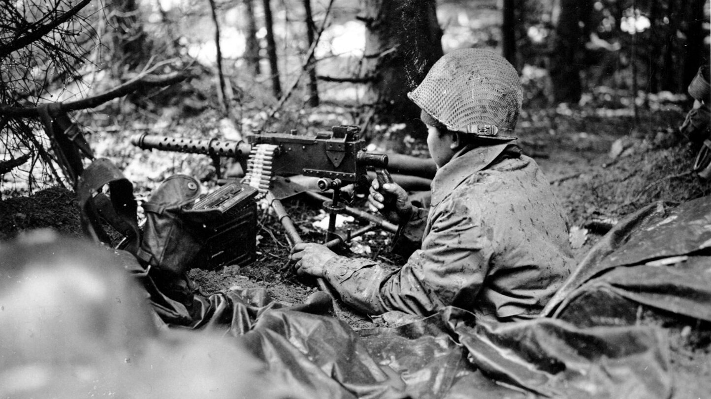  Manning a .30-caliber Browning machine gun, a Nisei soldier of the 442nd Regimental Combat Team wears a raincoat for protection against the harsh, wintry weather of November 1944 in the Vosges Mountains of France. 