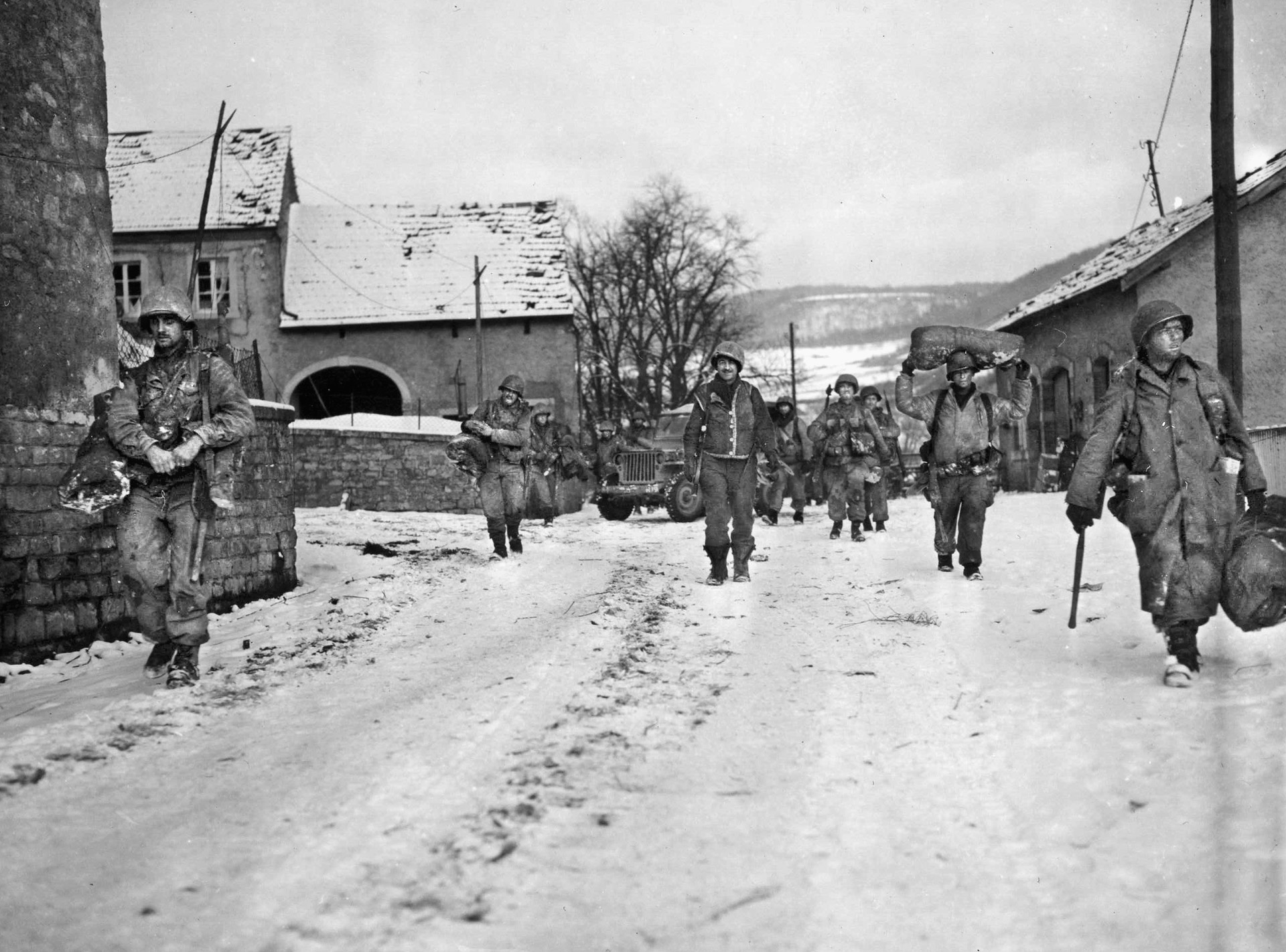 After the German counteroffensive had been halted, soldiers of the 8th Infantry Regiment, 4th Infantry Division, move through the snow-covered Luxembourg town of Moesdorf, January 21, 1945. Much hard fighting took place in small villages such as this one.