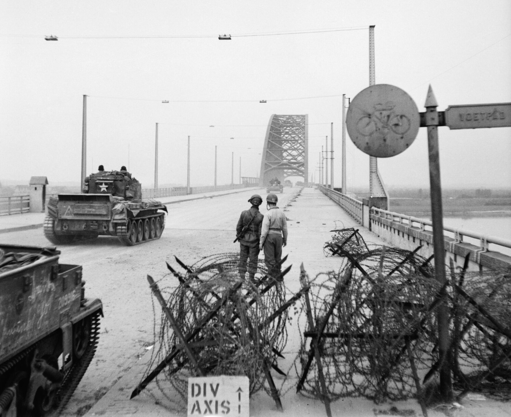 In this photo taken September 21, 1944, tanks of the 2nd Welsh Guards roll across the River Waal at Nijmegen while two soldiers look on.  