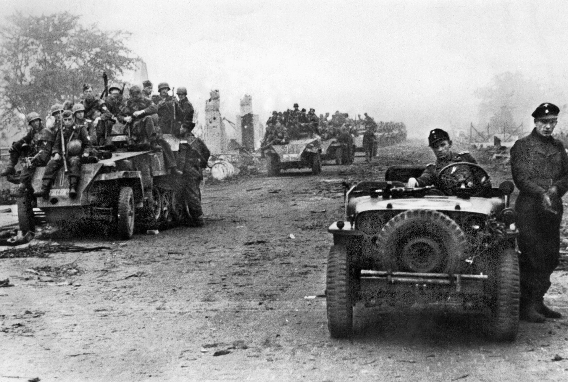 A German soldier sits at the wheel of a captured American Jeep while other troops ride atop several SdKfz. 250/1 armored cars. These heavily-armed troops rapidly regained the initiative after the early surprise of Allied airborne landings in the Netherlands and brought Operation Market-Garden to a halt.