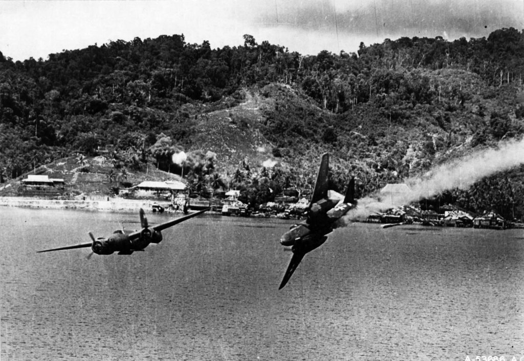 Two Douglas A-20 Havoc bombers from the U.S. 312th Bombardment Group execute a hazardous mission against a Japanese seaplane base in the South Pacific. Moments earlier, the bomber at right was hit by antiaircraft fire, and this image was taken just before the stricken plane plunged into the water below.