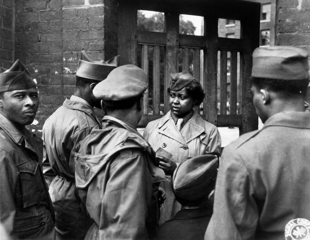 A member of the 6888th checks the identification card of an American soldier outside the battalion headquarters gate in Rouen, France, on May 26, 1945. The women were housed in a former French barracks.
