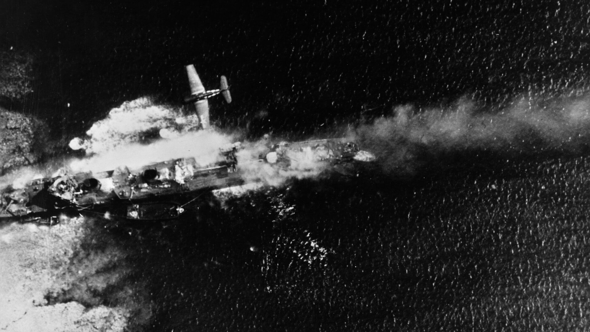 During the raid on Truk Lagoon nicknamed Operation Hailstone, February 16-17, 1944, a Grumman F6F-3 Hellcat fighter flies above the stricken Japanese destroyer Tachikaze.  Although the Japanese realized that a raid on Truk was imminent and moved many of their larger warships to safety, American aircraft from Task Force 58 still found numerous targets and inflicted heavy losses on enemy ships and shore installations.