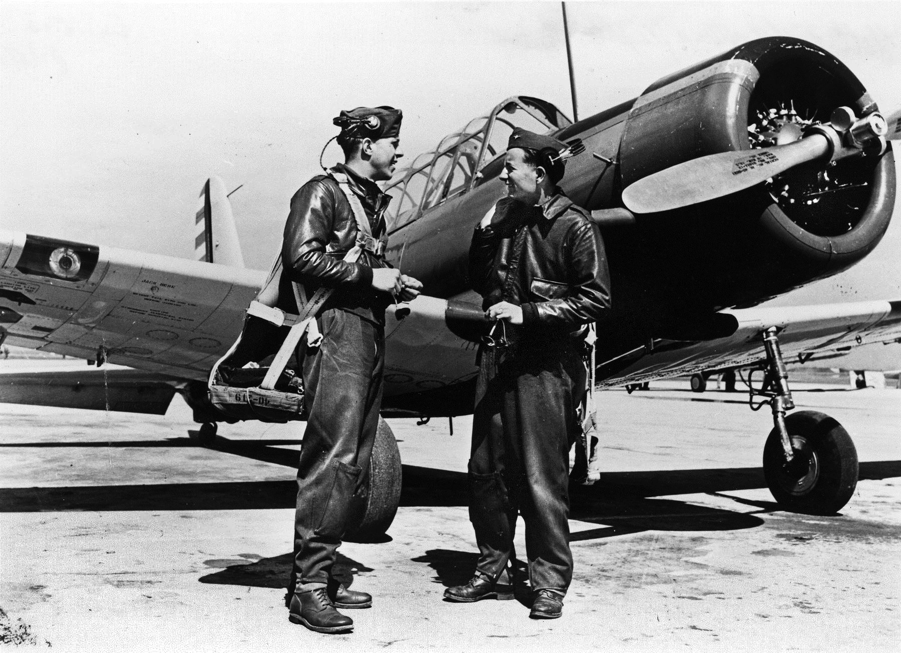 With their BT-13 basic trainer aircraft in the background, a pair of flight students in the enlisted pilot training program confer following a flight.