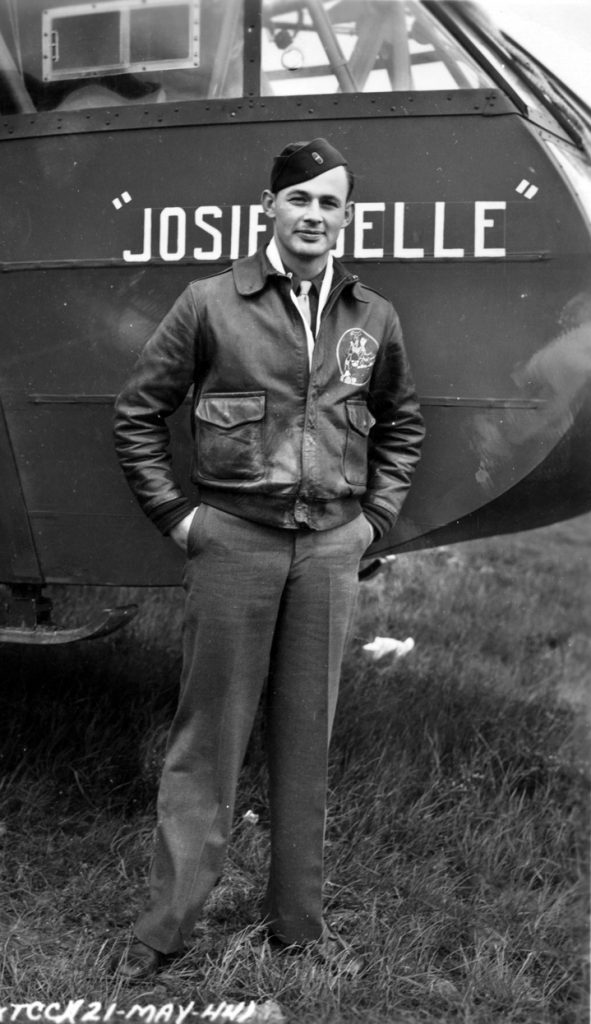 A Flight Officer glider pilot stands in front of one of the wood-and-canvas Waco aircraft that he was trained to fly.