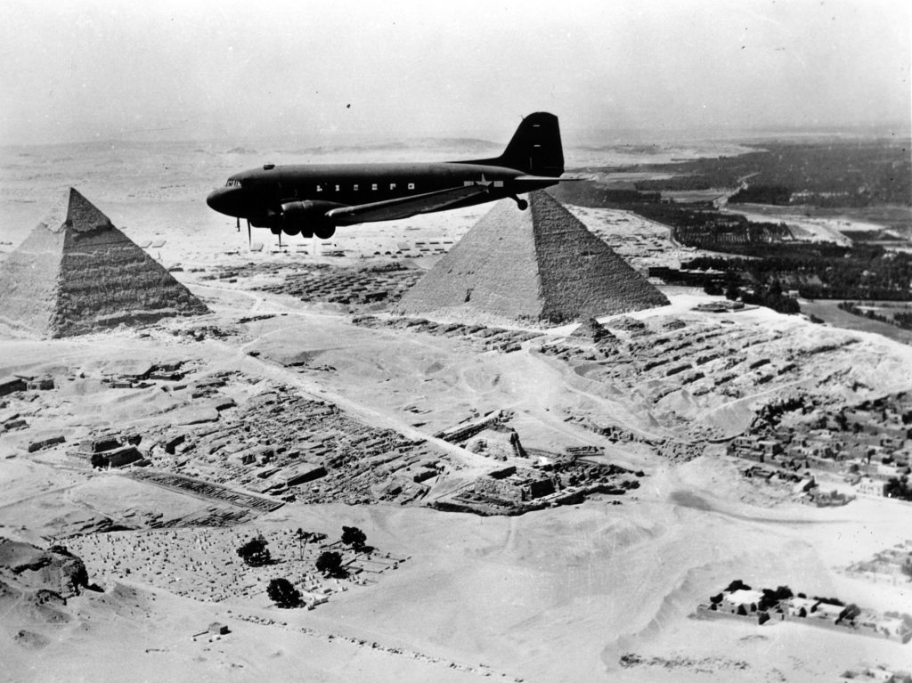 An Air Transport Command Douglas DC-3 flies above the Pyramids in Egypt.  Established in June 1942, Air Transport Command was the largest user of service pilots during World War II, and many former ATC pilots later signed contracts to fly for civilian airlines.