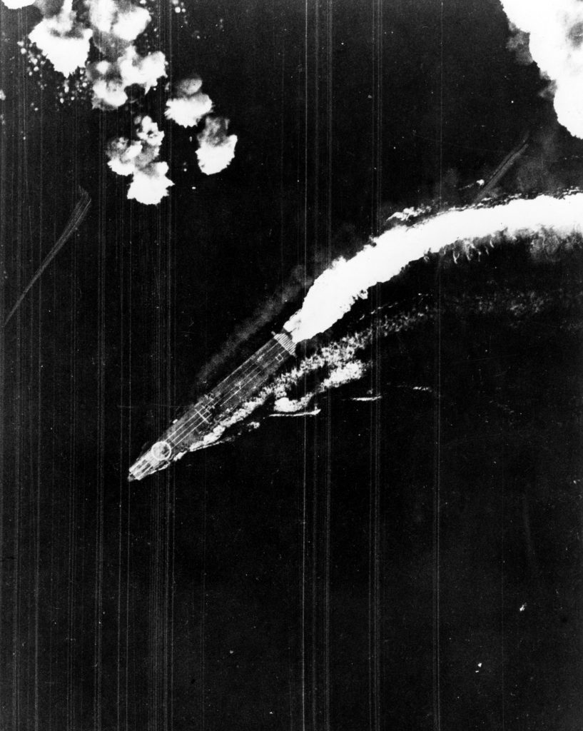 The Japanese aircraft carrier Hiryu maneuvers violently to escape bombs dropped from high altitude by an American Boeing B-17 Flying Fortress heavy bomber. No hits were scored during this raid.