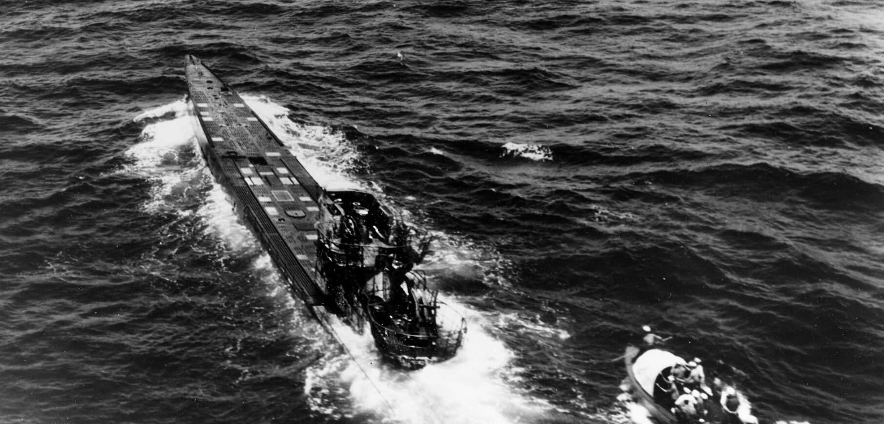 Despite the risk of U-505 being scuttled and blowing up, a boarding party from USS Pillsbury approaches the abandoned submarine, which is still underway. The Germans had intended to follow their abandonment doctrine and sink U-505 before it could be boarded.