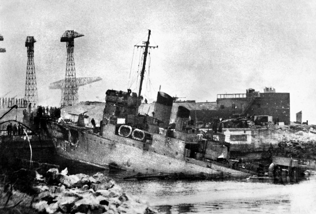 After the nocturnal raid, the destroyer HMS Campbeltown lies wedged into the Normandy dry dock at St. Nazaire. Hours after the fighting subsided, explosives aboard the old Lend-Lease destroyer detonated and severely damaged the surrounding facilities.