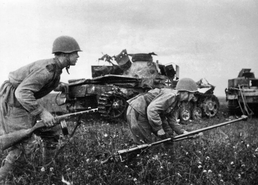 Soviet infantrymen crouch as they rush past the mangled wreckage of German tanks. The soldier at right carries a heavy antitank rifle, which was woefully ineffective against German medium and heavy tanks. 