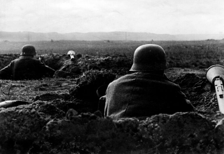 German soldiers in foxholes with panzerfausts within arm’s reach for immediate use await the onslaught of Soviet armor and infantry.