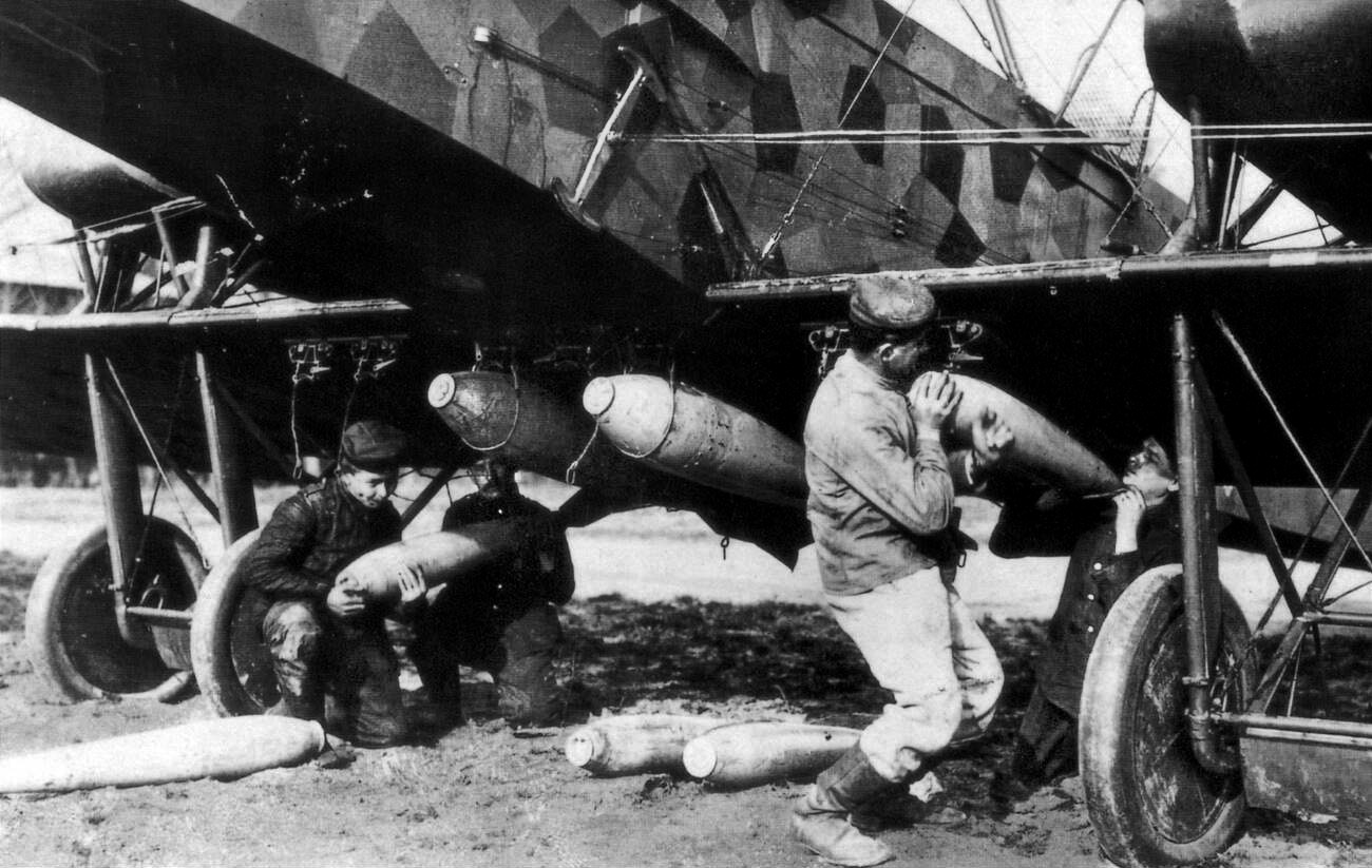 An ordnance specialist hangs bombs on the 78-foot wingspan of a Gotha bomber. Germany based an entire fleet of Gotha heavy bombers at airfields in occupied Belgium for strikes against Great Britain. 