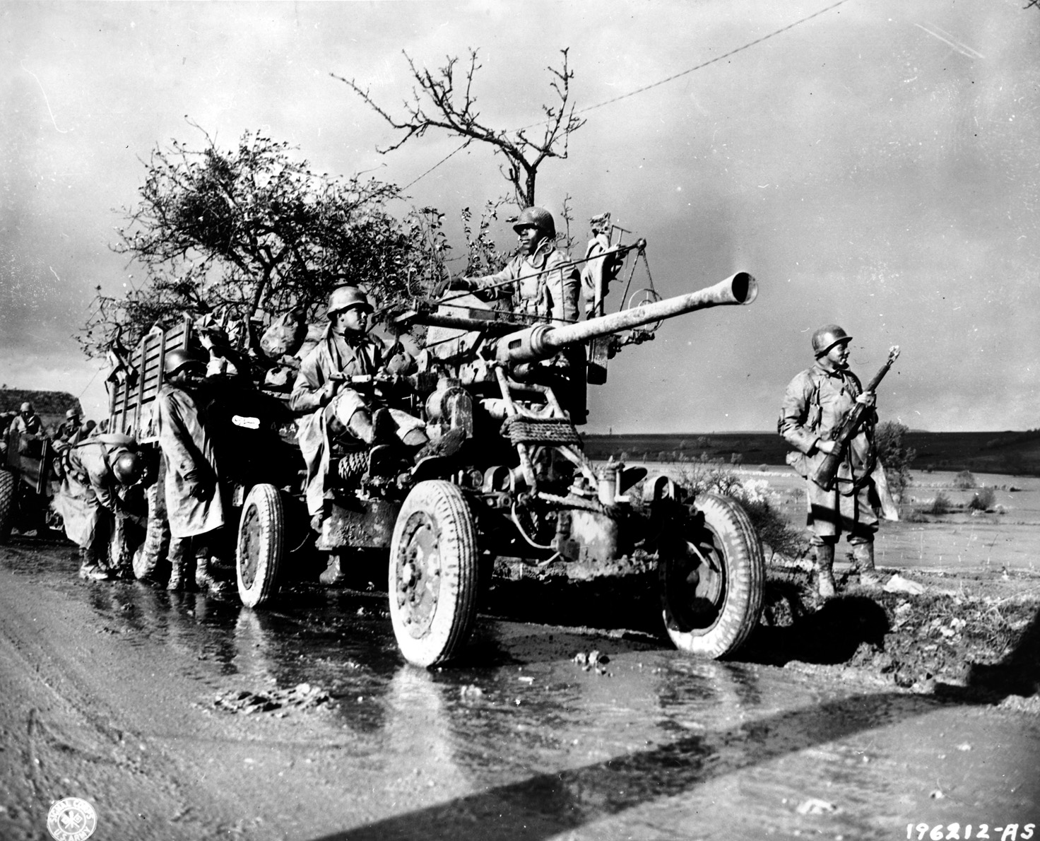 Members of the all-Black 452nd Anti-Aircraft Artillery Battalion stand watch for enemy planes while a convoy takes a short break.