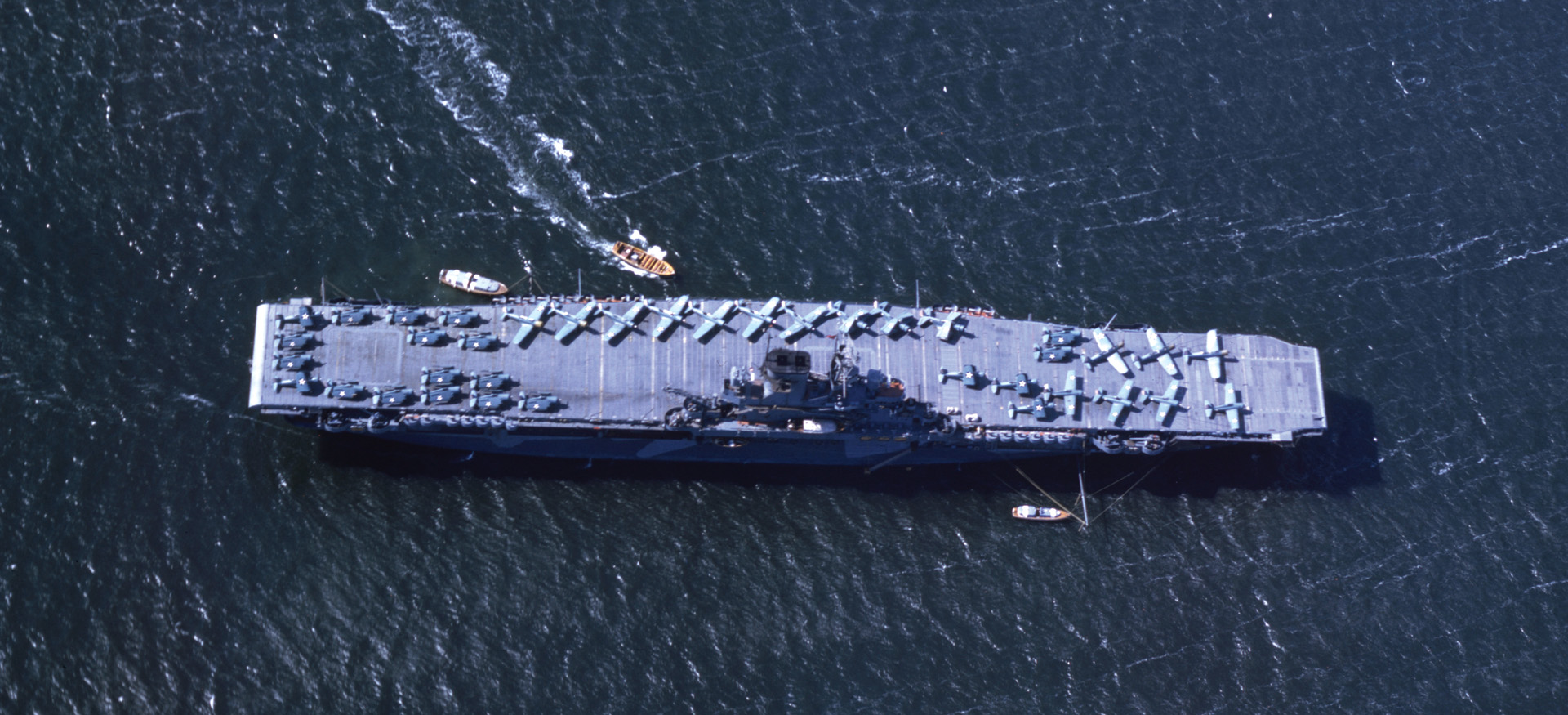 Aerial view of the USS Wasp (CV-7) near San Diego, California, in June 1942, shows 38 Hellcats and Dauntlesses, some with their wings folded, arrayed on the flight deck.