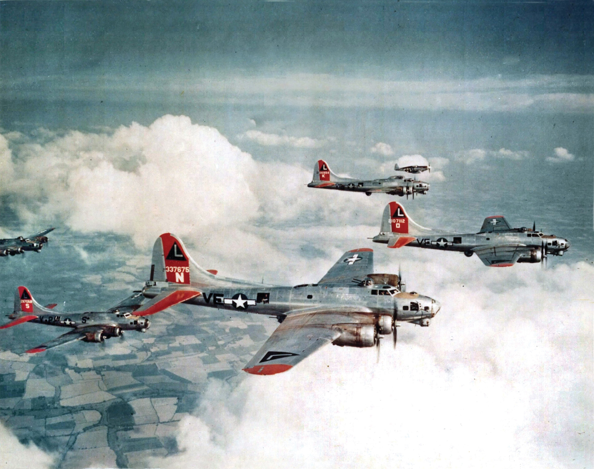 A P-51 Mustang (top) can be seen escorting a flight of B-17s from the 452nd Bomb Group on a mission deep into Nazi Germany. The introduction of P-51 escorts permitted long-range missions into the Third Reich.