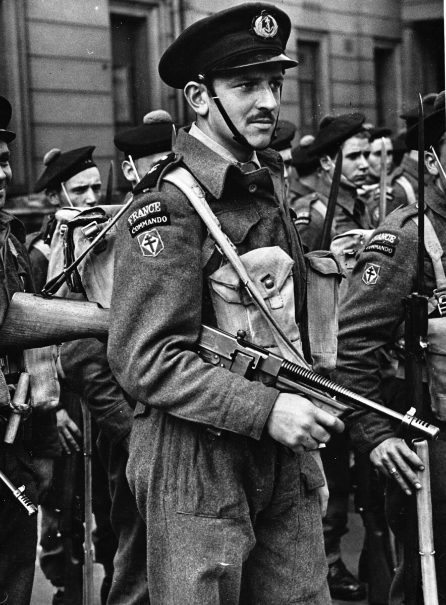 Armed with an American-made M-1921 Thompson submachine gun, a Free French Naval commando officer stands in formation with his men. French commandos took part in several operations, including the Normandy invasion on June 6, 1944.