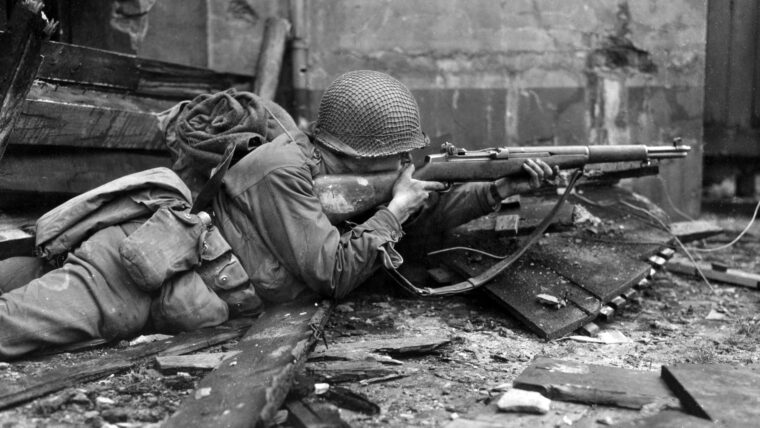 Lying in the rubble of Weisweiler, a German town between Aachen and Jülich, an American rifleman from the 84th Infantry Division takes aim at an enemy position. A massive American-British-Canadian offensive in early 1945 was designed to quickly break through enemy lines and cross the Rhine, but a combination of winter weather, flooded fields, and determined German resistance made progress slower than the Allies had hoped for.