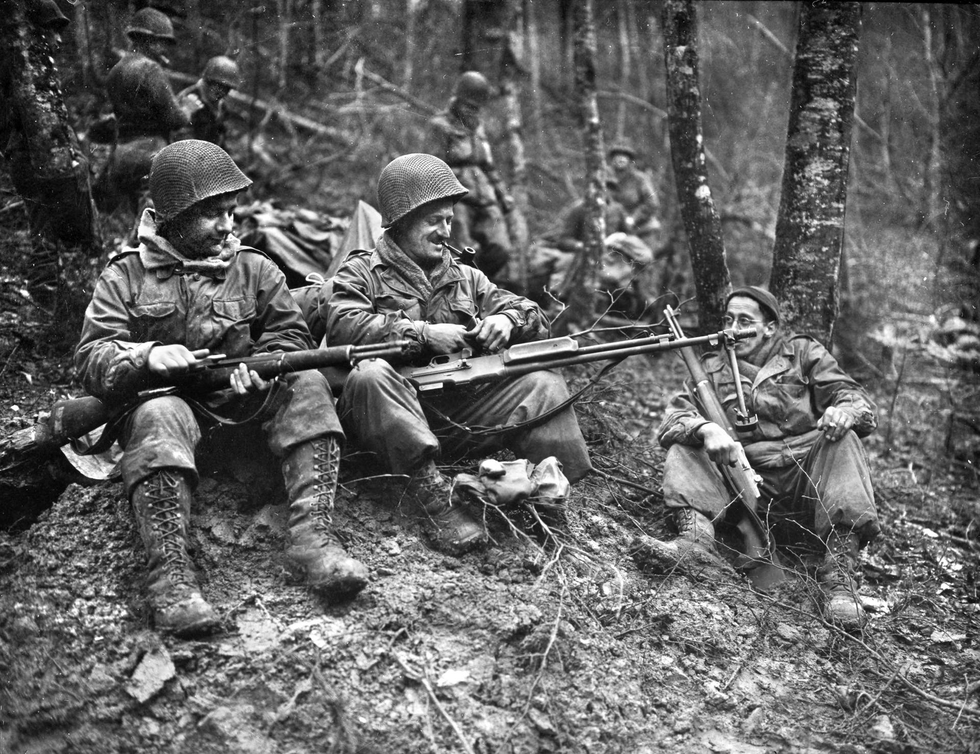 Three Massachusetts soldiers of the 417th Regiment, 75th Infantry Division, clean their weapons as they prepare to move up to the front line near Echternach, Luxembourg, February 8, 1945.
