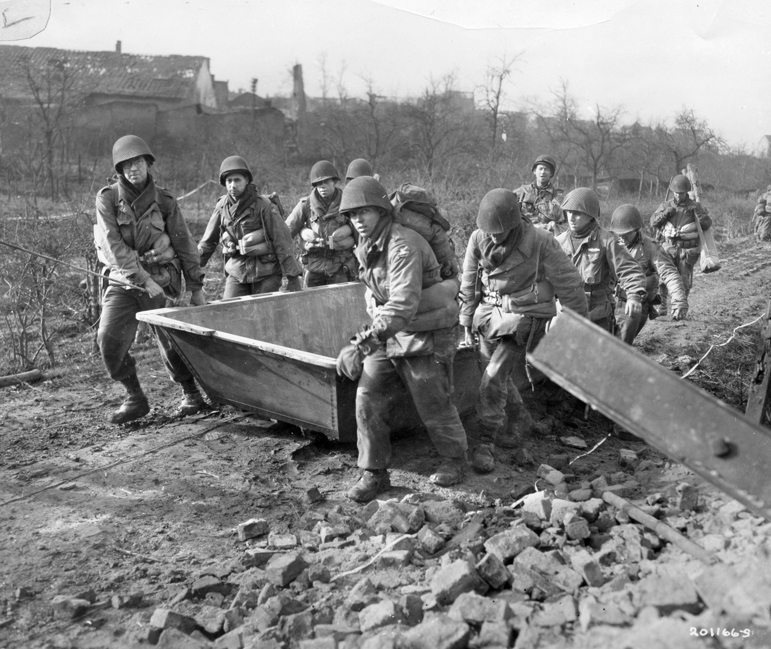 Combat engineers drag flat-bottomed assault boats toward the banks of the Roer River near Linnich, Germany, February 23, 1945, during the opening phase of Operation Grenade. The 84th Infantry Division made the crossing despite days of rain, boggy ground, and stiff enemy resistance.