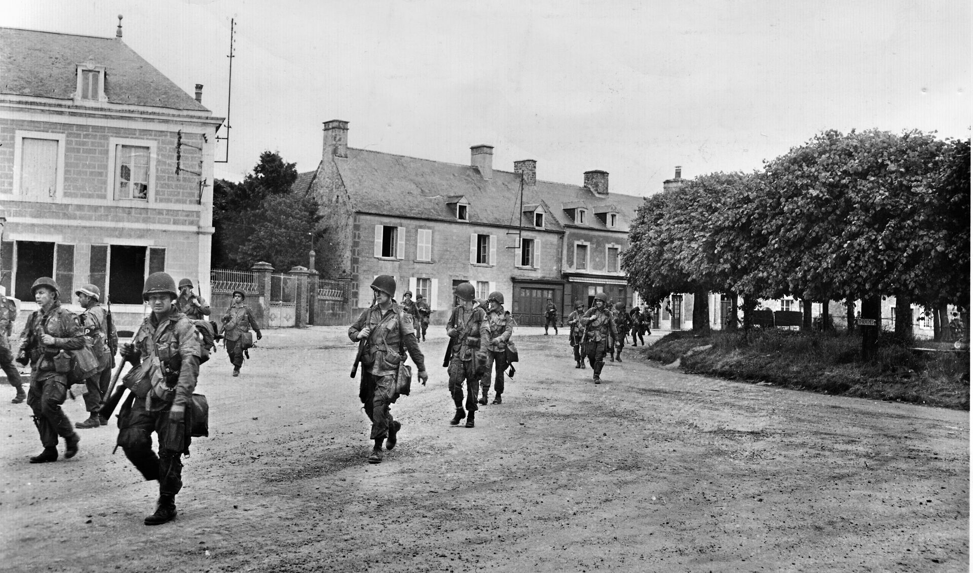 Striding through undamaged Ste. Marie-du-Mont like tourists, members of a 101st Airnborne unit advance southward toward Carentan, June 9, 1944.