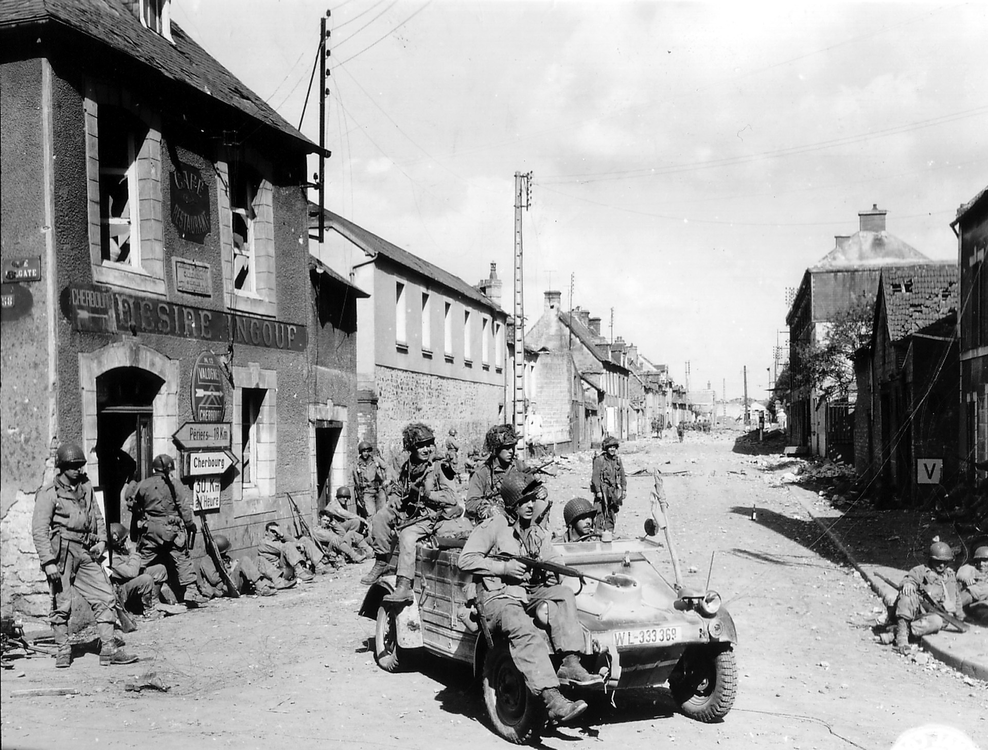 American paratroopers ride a captured Kubelwagen at the crossroads of the Rue Holgate and RN 13 in Carentan, June 12, 1944.
