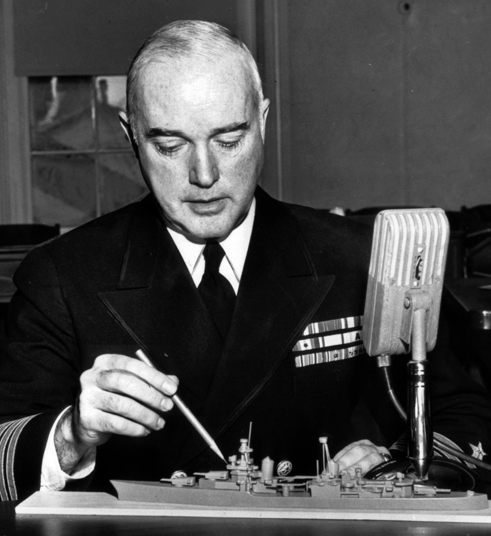 Using a model of his ship during his November 1945 court-martial, Captain Charles Butler McVay III points to where he was standing when two Japanese torpedoes tore into the Indy.