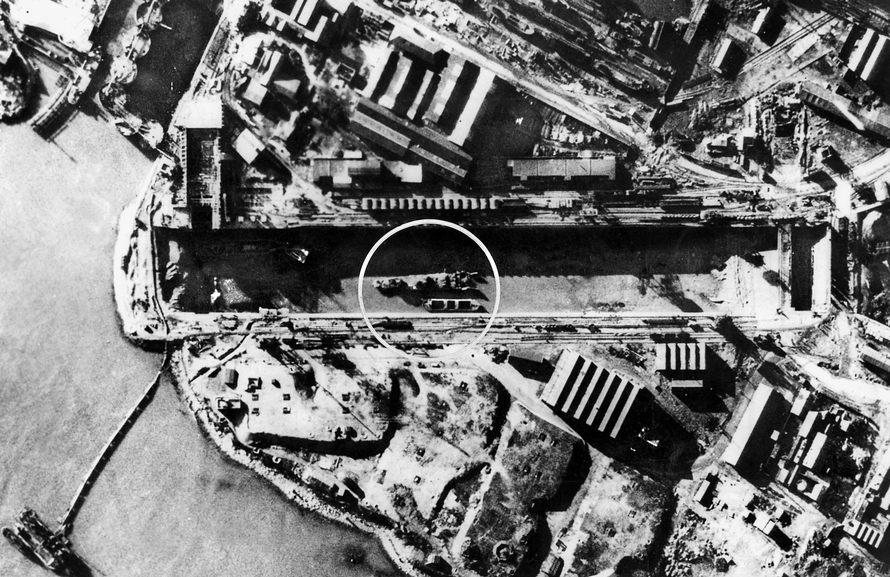 Aerial photo taken months after the raid shows the stern half of HMS Campbeltown (circled) lying on the bottom of the drained Normandie dry dock. Although the lock gate was repaired, the dry dock remained useless for the rest of the war, preventing its use by Germany’s largest warships.