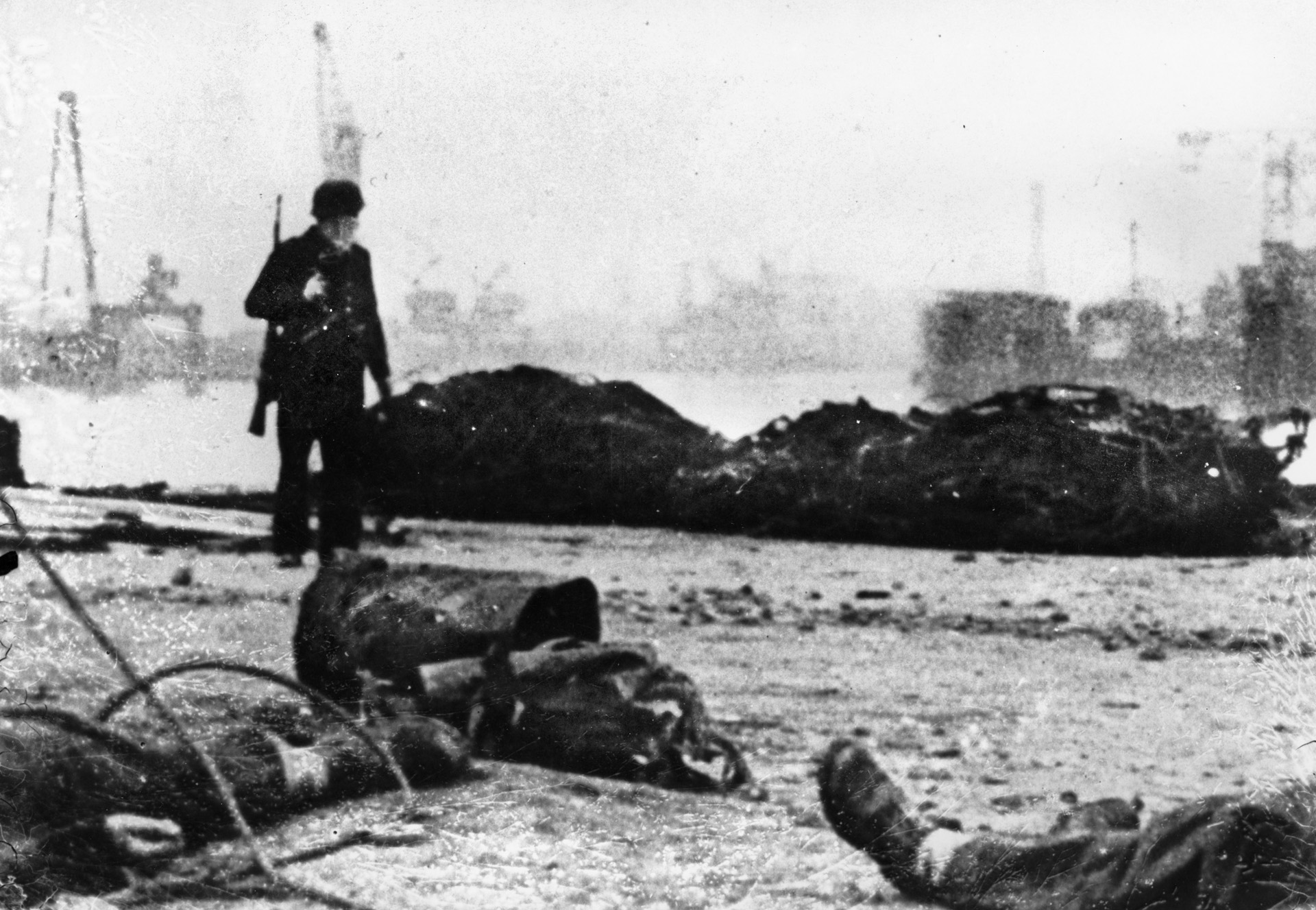 A German soldier inspects debris and British corpses along one of the docks at St. Nazaire.