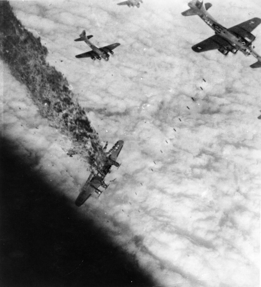 A B-17 (right) of the 486th Bomb Group drops its bombs over a synthetic oil plant at Merseburg, November 2, 1944, while another plane disintegrates in flames, a victim of flak. 