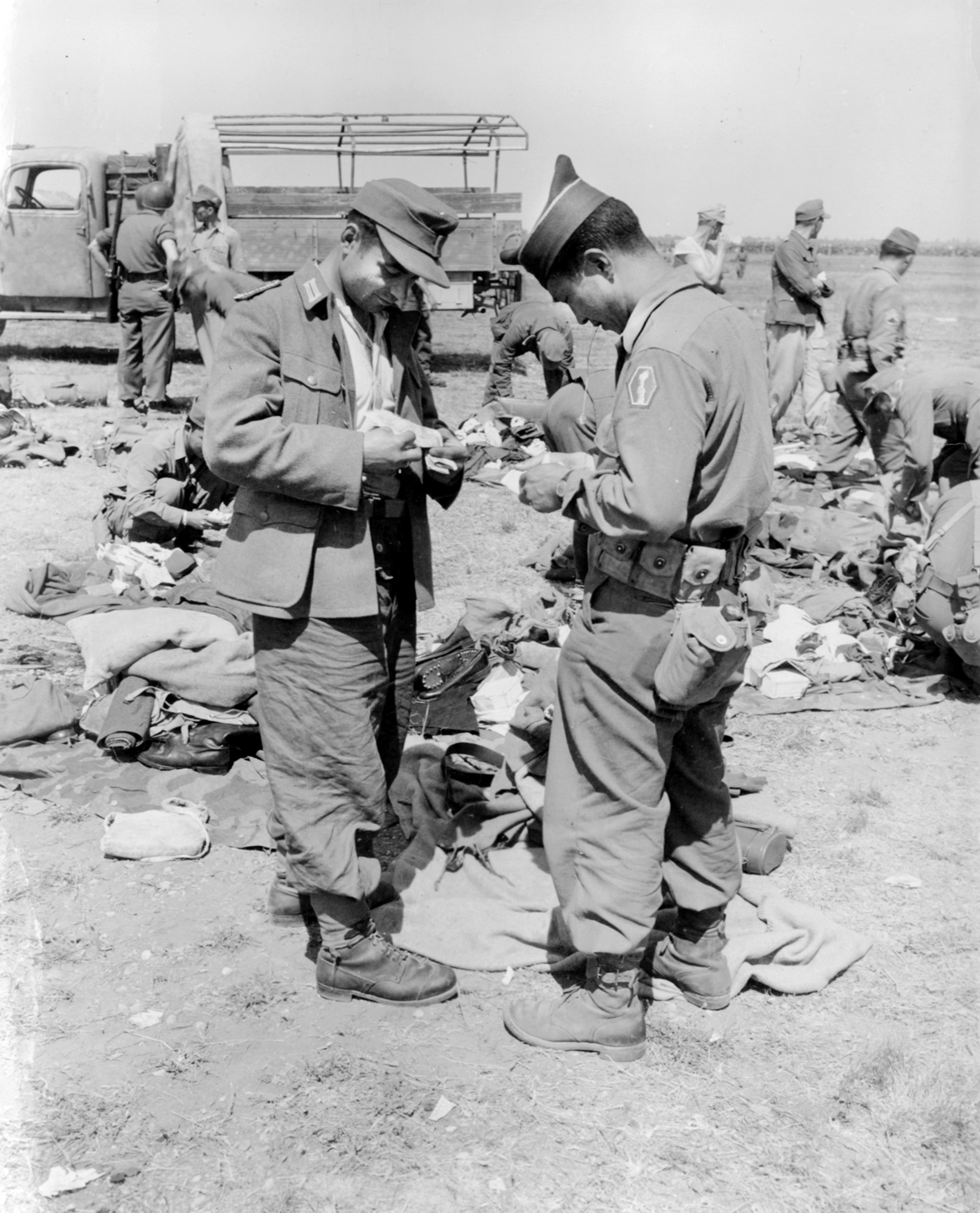 Private Akira Miyamoto of the 100th Infantry Battalion, inspects the papers of a German prisoner at Brescia, Italy, at the end of the war, May 1945. The Germans were surprised to be fighting against soldiers of Japanese descent. 