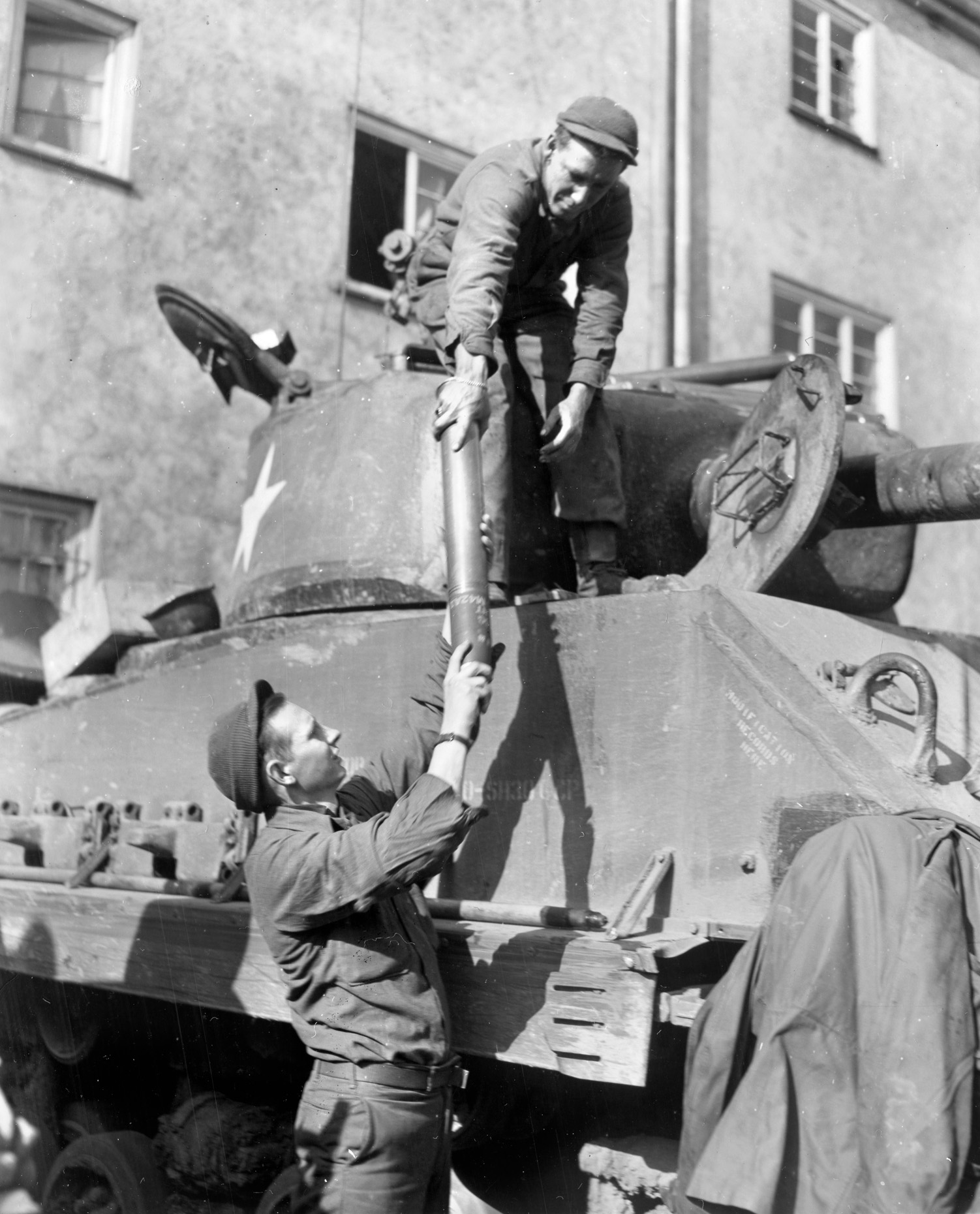During a lull in the fighting, two 10th Armored Division crewmen replenish their tank’s supply of ammunition “somewhere in Germany.” 