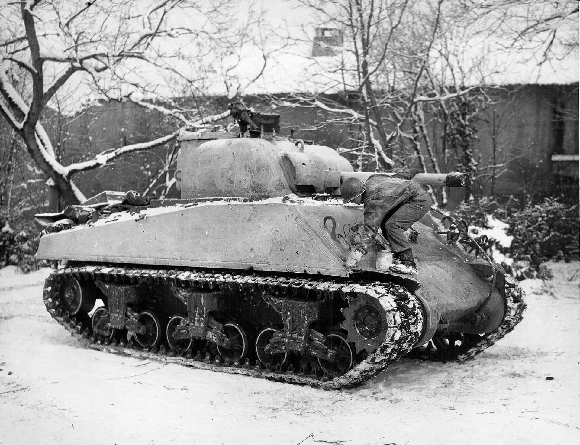 Tanker Sergeant Henry Perry, 11th Tank Battalion, applies whitewash to his Sherman in Belgium, January 1945. 