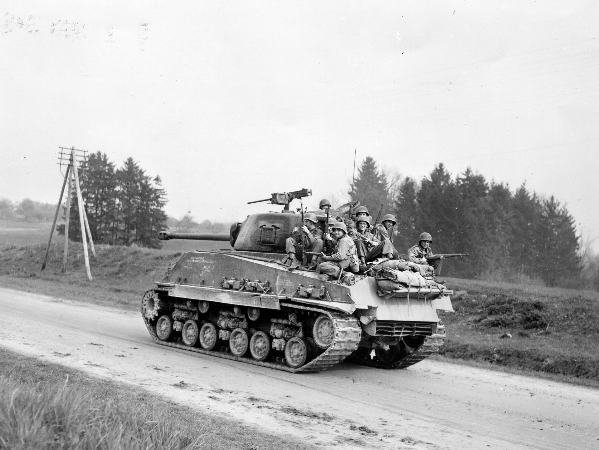 Why walk when you can ride? Infantrymen get a lift to the front atop a 10th Armored Division tank.