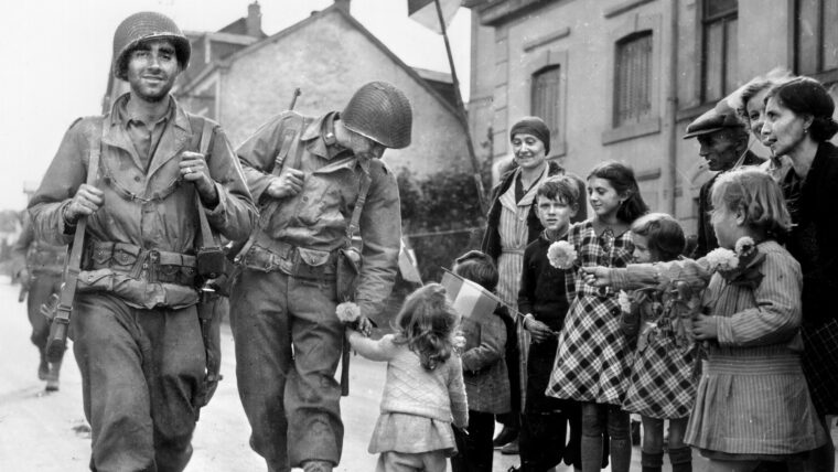 A little girl hands a flower to a lieutenant of the 110th Infantry Regiment, 28th Infantry Division, as flag-waving Luxembourgers welcome the liberating Yanks to their village, September 1944. Unfortunately, the celebration was premature; the Germans launched a counteroffensive that became known as the Battle of the Bulge three months later and nearly drove the Americans out of Luxembourg. Tom Myers was a soldier in the 110th Infantry whose unit was caught up in the chaos.