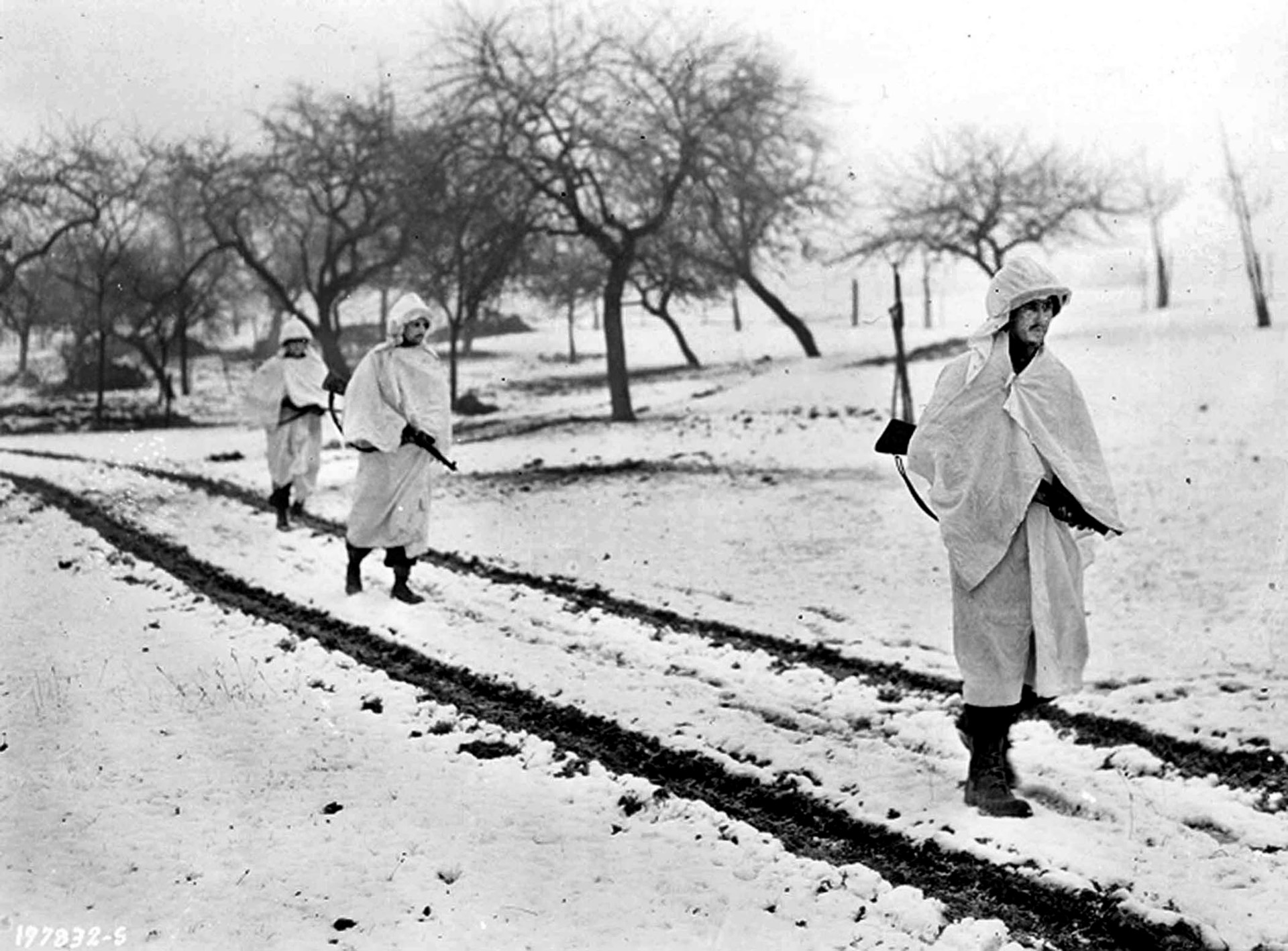 Covered with white sheets to help them blend in with the snow, an American patrol sets out during the Battle of the Bulge. Tom Myers recalls encountering German soldiers wearing American uniforms during one such patrol.