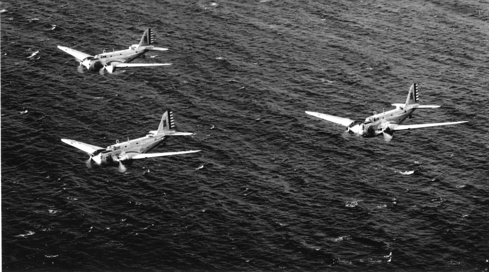 A flight of B-18 bombers wings its way over open water. The 27th Bombardment Group flew B-18s while it was stationed in Australia.