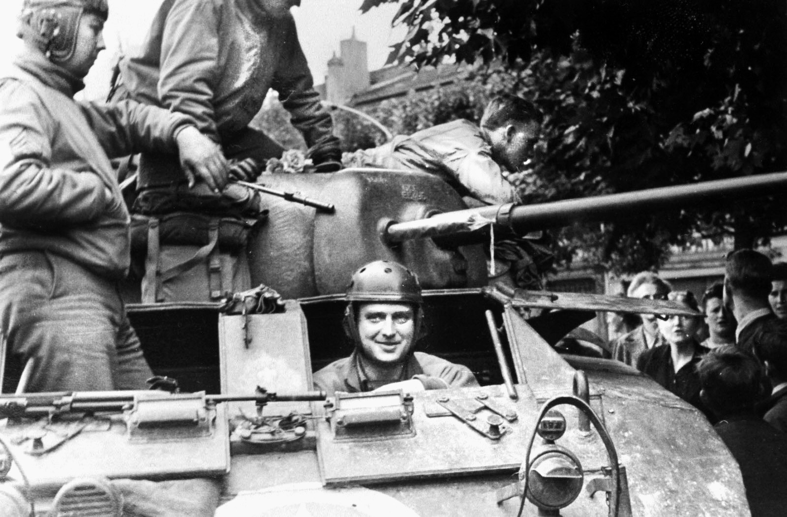 A tank crew takes a breather in the town of Luneville. The driver has just emerged from his hatch beneath the barrel of the 37mm main weapon. 