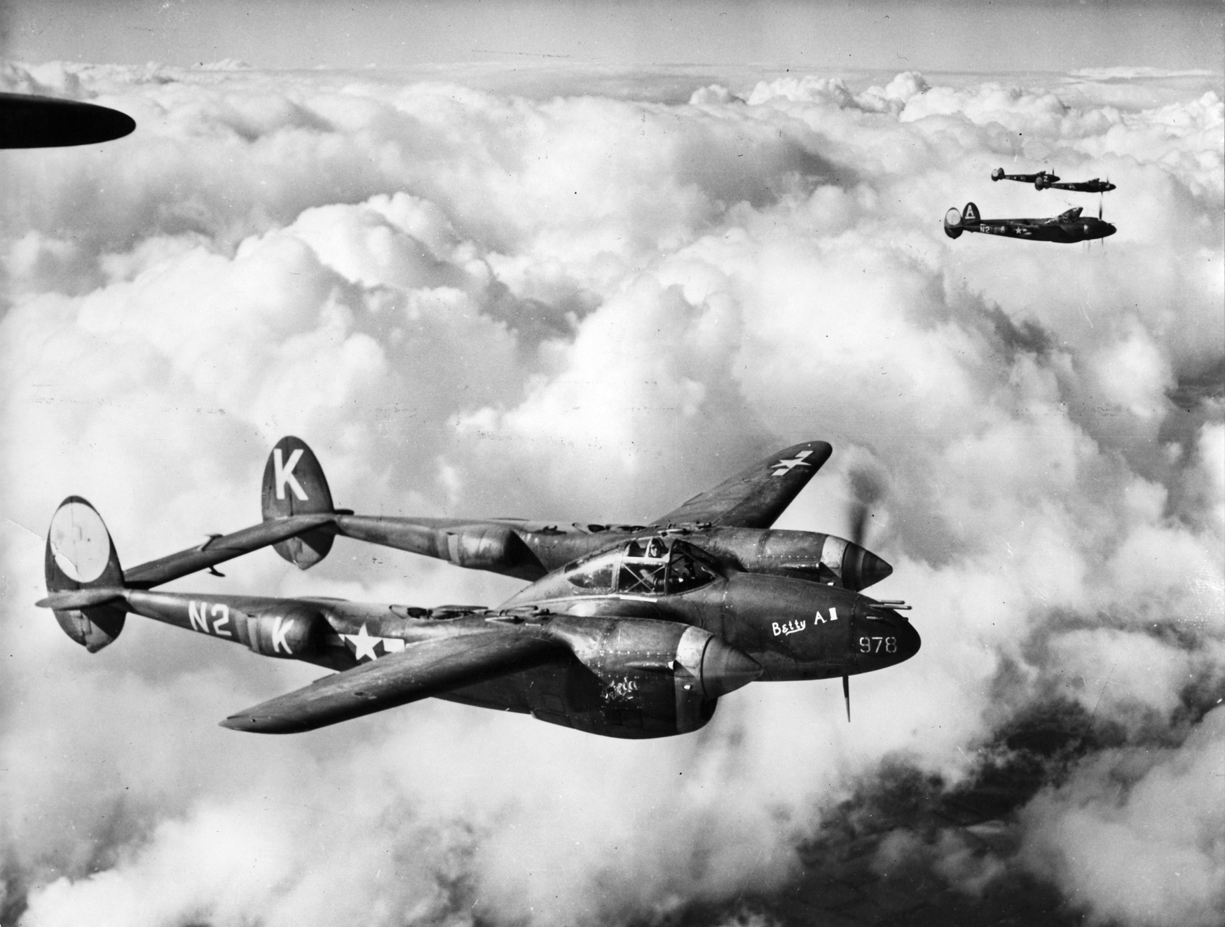 These P-38 fighters of the 383rd Fighter Squadron based in England are shown in flight in 1944.  The versatile Lockheed design served in all theaters of World War II and in roles as a bomber escort, fighter bomber, and reconnaissance aircraft. 