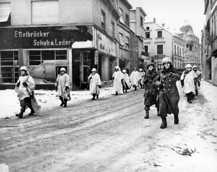 Soldiers of the U.S. 5th Infantry Division, part of General George S. Patton’s Third Army, march through the snowy streets of the town of Ettelbruck, Luxembourg, in January 1945. These soldiers were involved in the Allied counteroffensive that reduced the bulge formed by the German Ardennes Offensive. Some of these soldiers are wearing white sheets as camouflage.