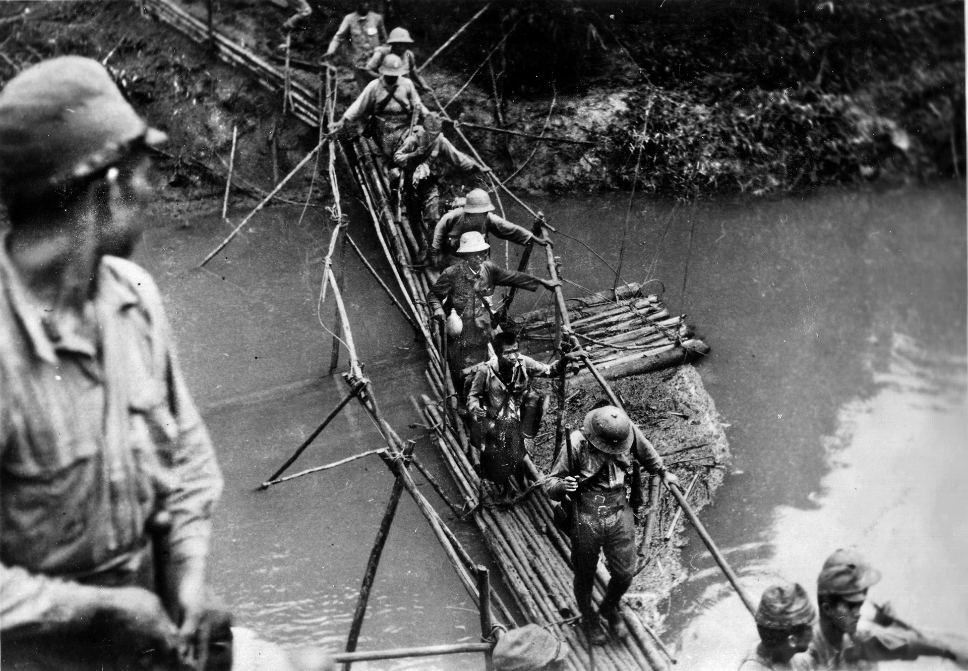 Japanese troops cross a river in Burma via an unsteady bridge. The Japanese were well trained in jungle fighting and withstood the privations of harsh conditions during their advance in Burma. 