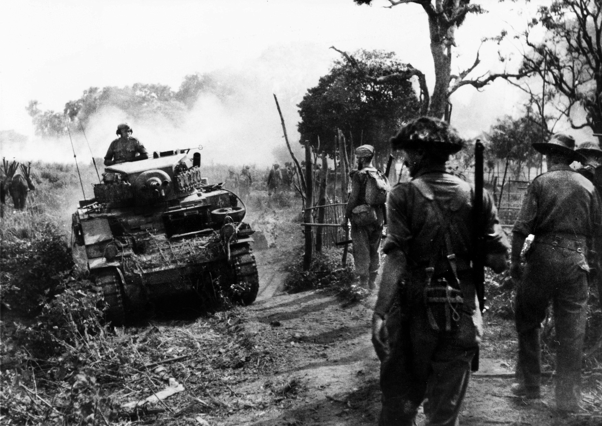 Traversing the rugged terrain of the interior of Burma, tanks of the 19th Indian “Dagger” Division roll down a dirt path while infantrymen pause to glance at the armored vehicles. General William Slim, commander of the British 14th Army, led his forces from the brink of total defeat to victory over the Japanese in the China-Burma-India Theater.