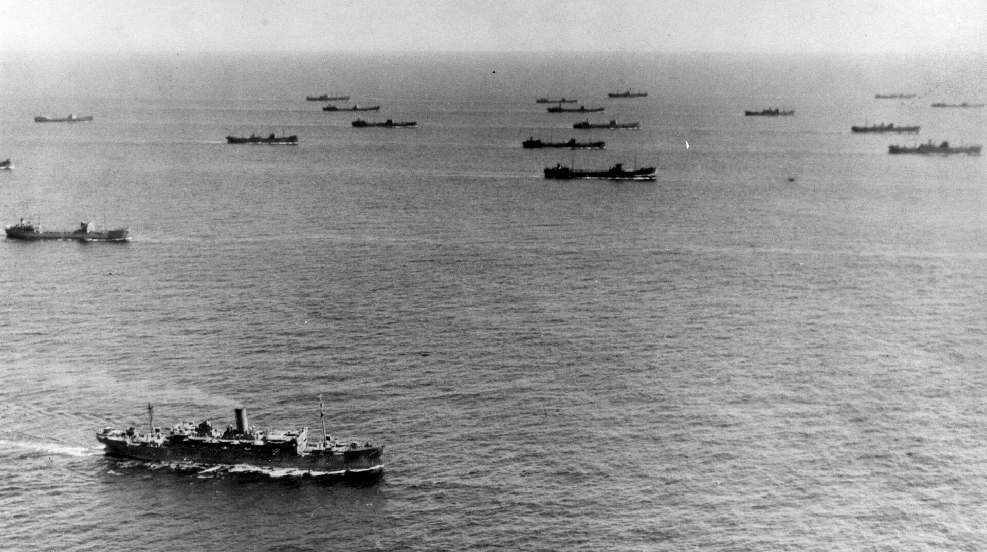 A large Allied convoy, the lifeline to the British Isles, stretches into the distance in preparation for the perilous passage across the Atlantic Ocean from North America to Britain. This photo was taken off the coast of Newfoundland, and encounters with marauding Nazi U-boats were expected along the way.