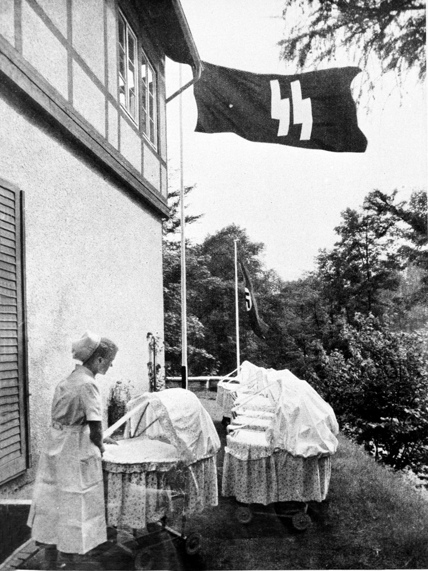The SS flag flies above a nurse who pushes baby carriages at a Lebensborn home in Germany.  