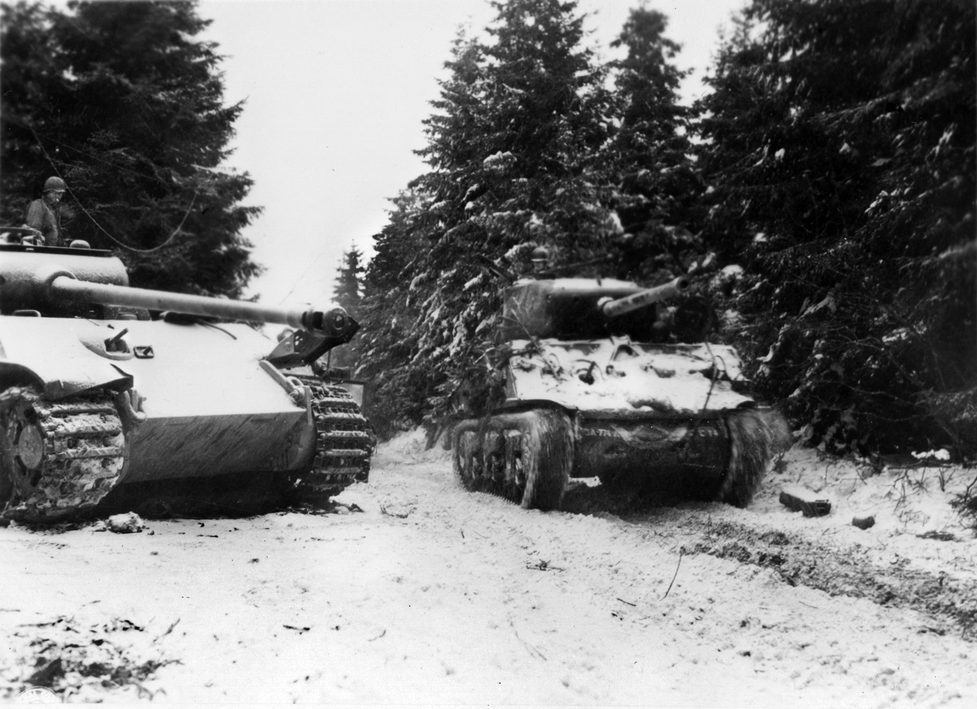 Forging ahead, tanks of the U.S. Third Armored Division pass a disabled German PzKpfw. V Panther medium tank that had been abandoned by retreating Germans. The Panther, with its high-velocity 75mm cannon, is considered by many to be the best tank of World War II.