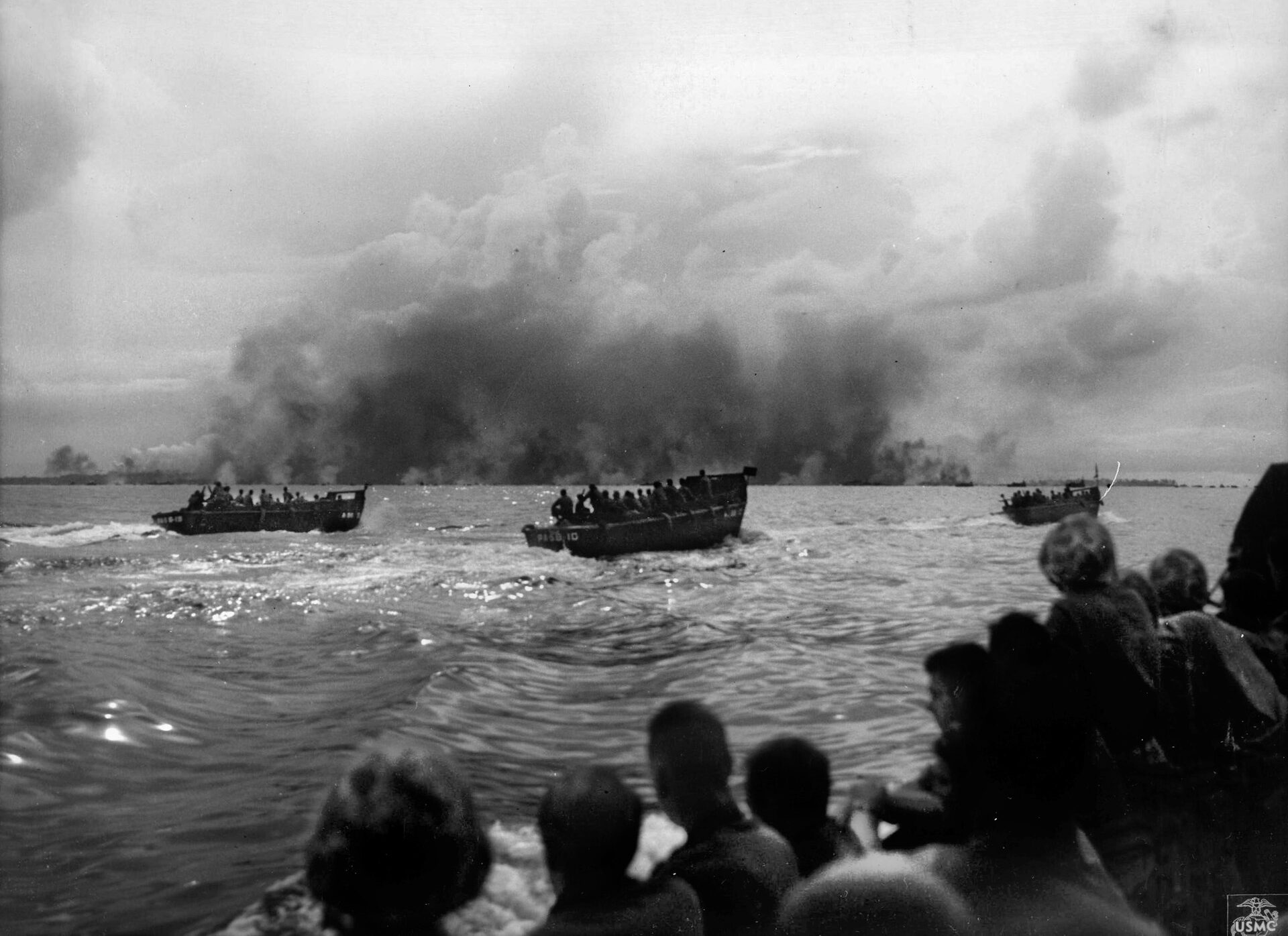 A pall of smoke from naval and air bombardment covers the small island of Peleliu as landing craft carrying the invading U.S. Marines turn for their runs into the contested beaches.