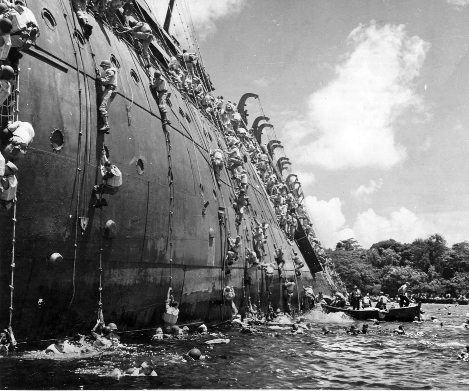 Men scramble down ropes hastily thrown from the foundering troop transport SS  President Coolidge, which struck a mine in the harbor of Espiritu Santo in October 1942.