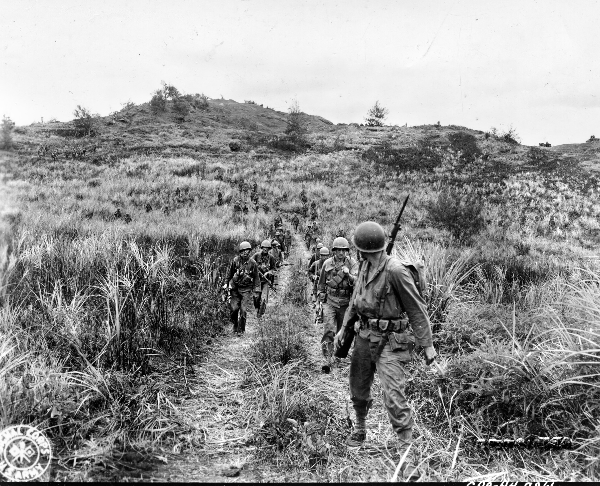A patrol of the 77th Infantry Division makes its way along a dirt path on the island of Guam in the Marianas in the summer of 1944. The capture of Guam was a key event in the securing of the Marianas for forward air bases from which American heavy B-29 Superfortress bombers could strike the Japanese home islands.
