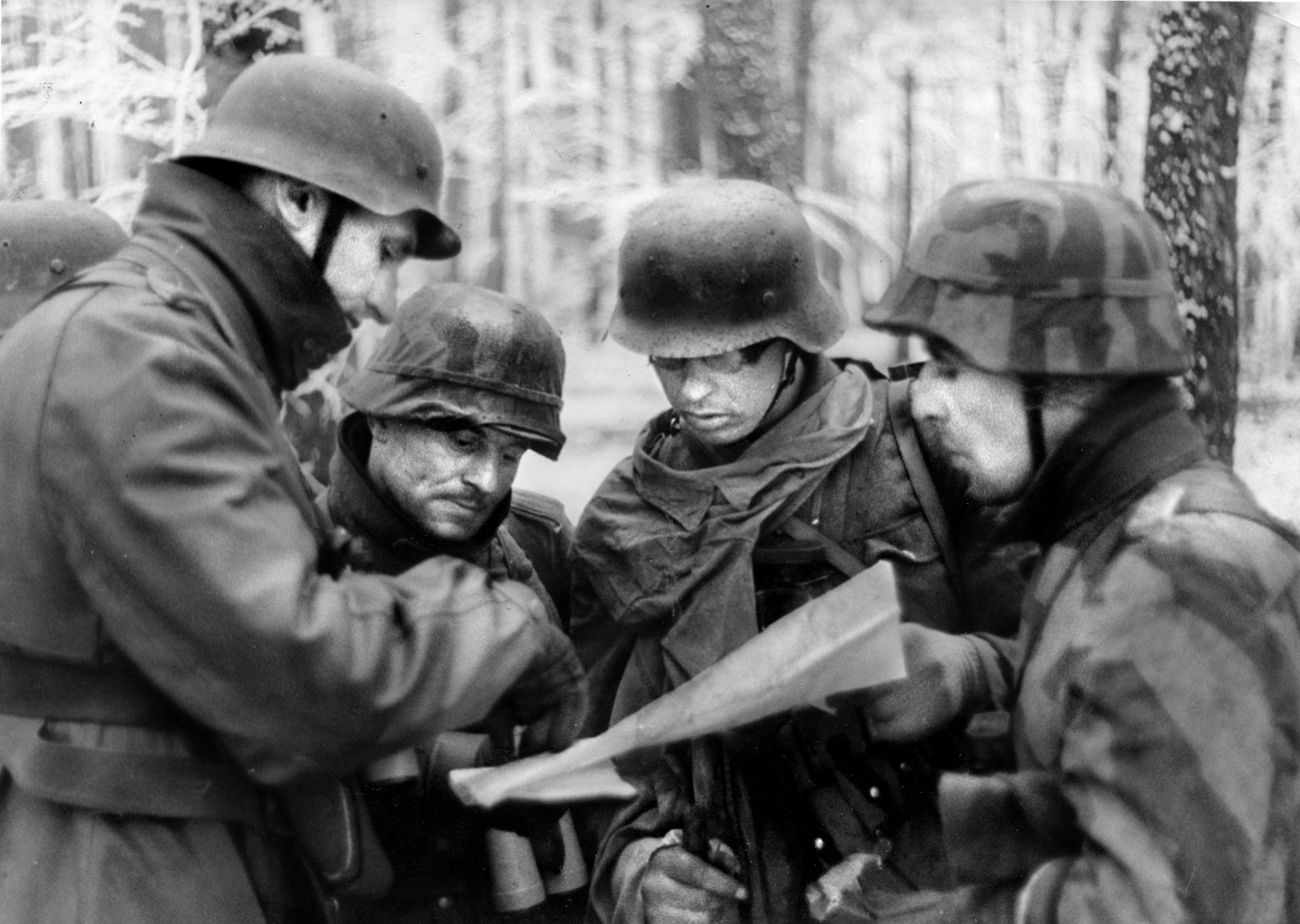 Prior to an assault during the Battle of the Bulge, a German battalion commander gives last-minute instructions to a group of soldiers poring over a map of the vicinity. Lieutenant Lyle Bouck of the 394th I&R Platoon ordered his men to hold their fire when a Belgian girl approached from a nearby house and spoke to a gathering of German officers before the fighting at Lanzerath began.