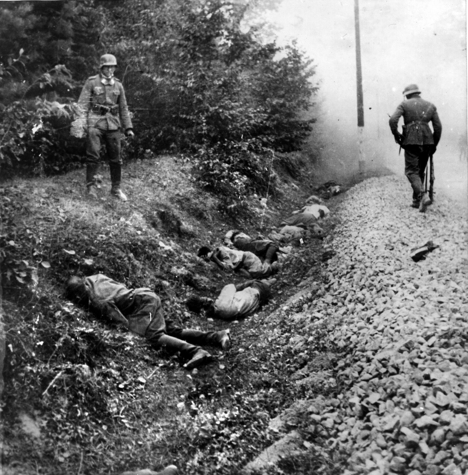 German soldiers gaze at the corpses of Polish soldiers littering a ditch alongside a country road, executed after their surrender. The Germans and the Red Army engaged in atrocities against the Polish military and civilian population as well.