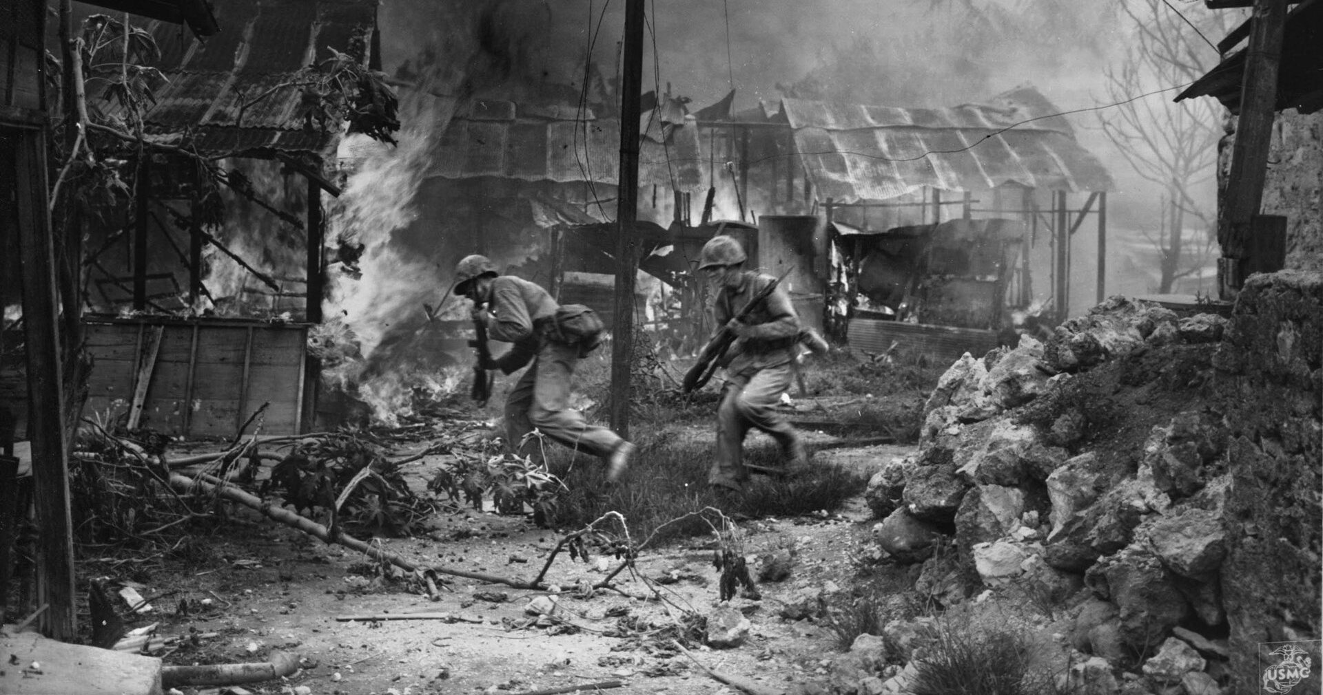 Under heavy fire from Japanese defenders, Marines move quickly through the rubble of Garapan, principal city on the island of Saipan. The battle for Garapan in July 1944 was the first experience of street fighting for American Marines in the Pacific.